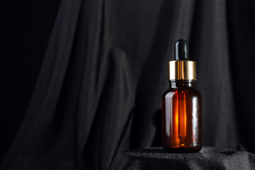 Brown bottle with dropper with a beauty serum on black background. Glass packaging for cosmetic...