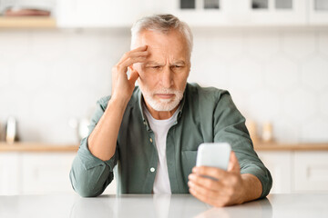 Myopia Concept. Senior man squinting while looking at smartphone screen