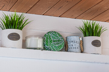 Artificial flowers in white vases stand on a shelf in the house, home decor has a place for 
