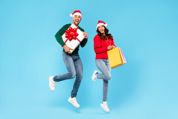 Joyful Young Couple Holding Present Box And Shopper Bags, Studio