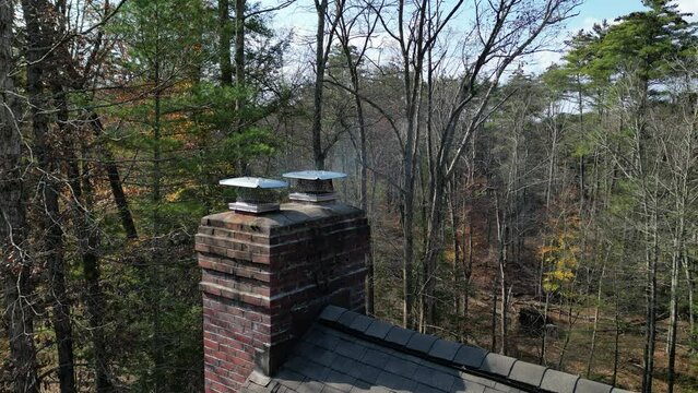 smoke coming from chimey of a suburban home in the woods (rural house drone footage shot from above) shingles, roofing, fireplace exhaust, country home, rustic luxury architecture