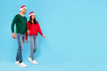 couple in Santa hats and casual standing on blue background