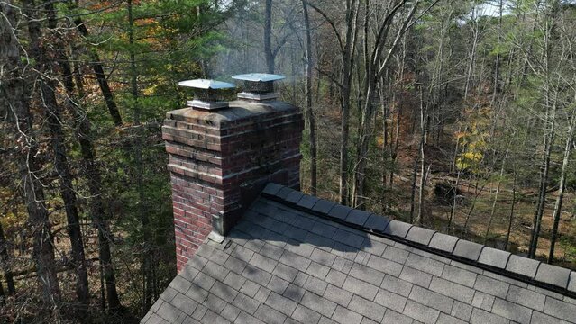 smoke coming from chimey of a suburban home in the woods (rural house drone footage shot from above) shingles, roofing, fireplace exhaust, country home, rustic luxury architecture