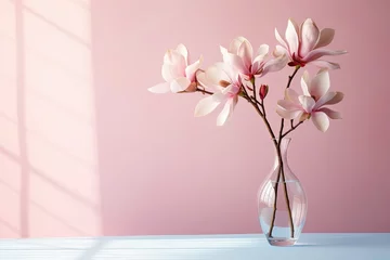 Zelfklevend Fotobehang Beautiful pink magnolia flower in transparent glass vase standing on white table, sunlight on pastel pink wall. © Bargais