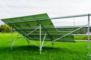 Fototapeta premium Installation of solar panels on metal frames in a green meadow, unfinished solar power plant