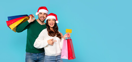 couple with Santa hats and bags holding credit card, studio