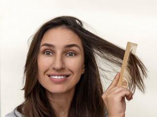 happy millennial woman showing healthy hair,holding elastic and oil treatment,many plastic...