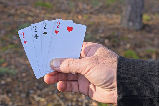 hand holding four playing cards with deuces on the street