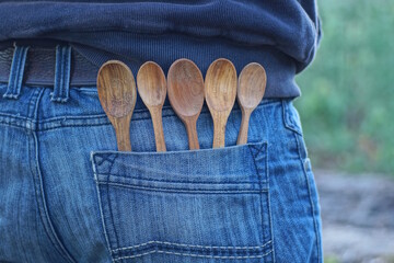 five brown wooden spoons in a blue jeans pocket on a man on the street