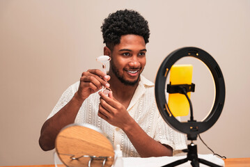 Latin man smiling while recording a video with ring light with a facial roller