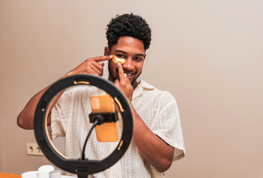 Young latin man applying skincare with face patch in front of ring light