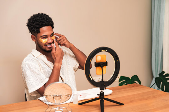 Young latin man applying skincare with face patch in front of ring light
