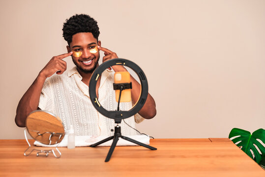 Young latin man applying skincare with face patch in front of ring light