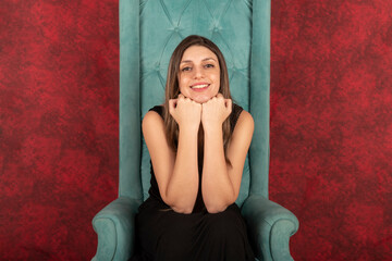 Blonde woman sitting in a queen-style armchair looking at the camera smiling