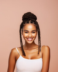 Half-length portrait of young, happy, smiling African black model girl with pigtail hairstyle and in white tank top with straps looks at the camera isolated against soft pastel pink background