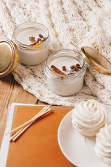 Cozy candles with spices on the knitted background with magazines. Coziness, festive home, holiday concept, holidays card.