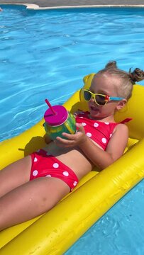Cute little girl lying on inflatable mattress in swimming pool with blue water on warm summer day on tropical vacations. Summertime activities concept. Cute little girl sunbathing on air mattress