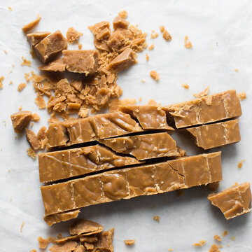 Crumbly Brown sugar fudge being cut on a marble tray, caramel fudge being cut into pieces, crumbly fudge candy on a marble tray