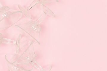 Small crystal glasses scattered on a pink background. Concept with place for text.