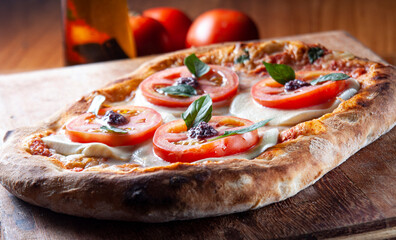 pizza, tomatoes, tapenade, mozzarella and basil. on wooden table