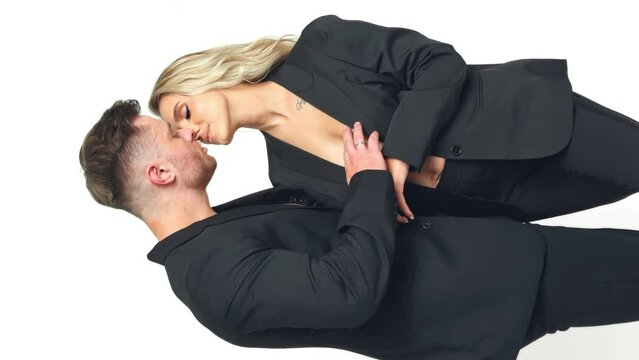 Sportive man caressing blonde woman. Caucasian couple kissing and stroking each other. Vertical screen. White backdrop.