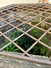 A view through a metal grating to a hole in the ground