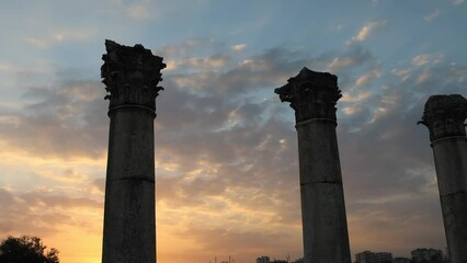 Sunset drapes golden light over a row of Greek columns in Pompeliopolis, Mersin. These ancient columns stand in solemn testimony to history. Long shadows play between columns, echoing tales of yore - Powered by Adobe
