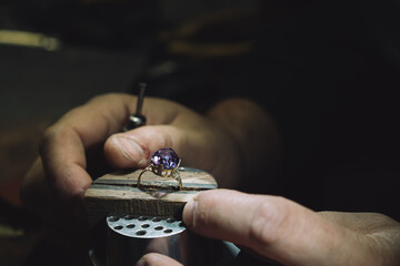 Close up of a goldsmith's hand making a gold or silver ring or a diamond using goldsmith's tools. For this work it takes precision and patience. Concept of: tradition, luxury, jewelry. - obrazy, fototapety, plakaty
