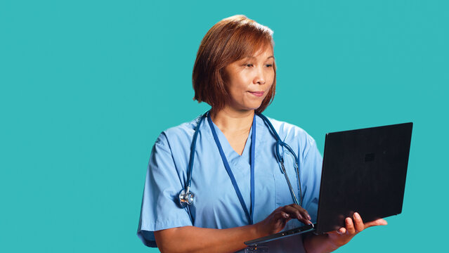Nurse imputing medical checkup data on notebook, unhappy with dissapointing patient health results. Healthcare professionist isolated over studio background scheduling future appointment