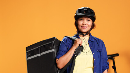 Close up portrait shot of upbeat smiling BIPOC bicycle rider holding professional thermic bag,...