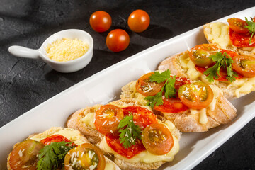 Starter or antipasto - Bruschetta with slices of Spanish sausage on French bread with cherry tomatoes and mozzarella cheese