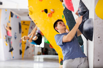 Caucasian young man exercising in climbing gym on wall.