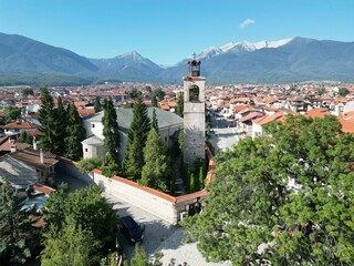 Aerial shot of Holy Trinity Church around houses and green trees in Bansko, Bulgaria