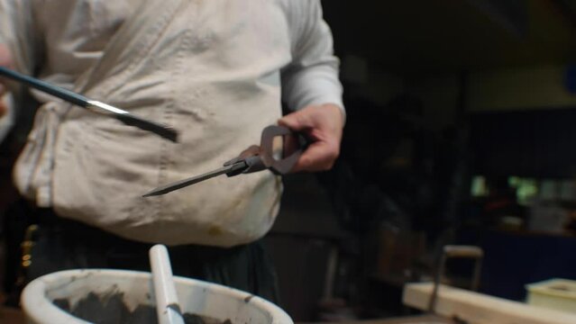 Blacksmith spreading mineral oil on a knife before sharpening