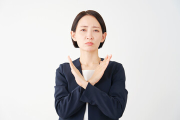 腕でばつ印のジェスチャーをする中年のビジネスウーマン　白背景