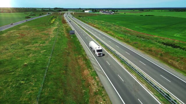 Tanker truck for transporting gas, fuel or petroleum moves along a wide country highway. Transportation by land, cargo and oil delivery. Aerial view. 4k footage