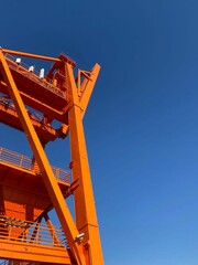 Vertical shot of an orange metal construction on the background of the blue sky