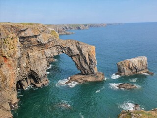 Top view of the natural arch, rugged limestone of Green Bridge of Wales surrounded by a scenic sea