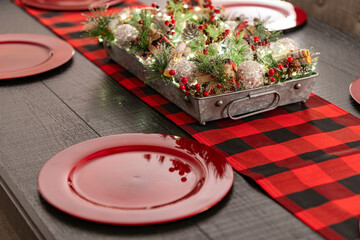 Decorated Centerpiece on a wooden table with Christmas settings and Christmas decorations and lights in the background.