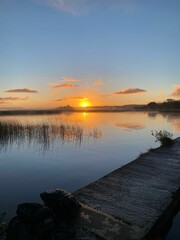 Vertical shot of a wooden pier on a tranquil lake at sunset