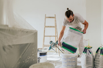 A plasterer is adding plaster into a bucket and preparing for plastering.