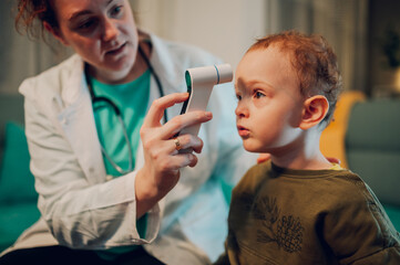 Close up of a pediatrician using thermometer and checking child's temperature.