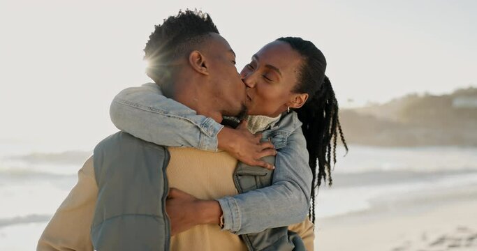 Kiss, happy and black couple at the beach with hug for love, date and bonding on holiday. Laughing, nature and an African man and woman with care and affection at the sea for a vacation or honeymoon