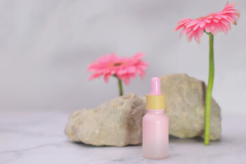 Pink serum oil face care bottle with flower gerberaand stone, mockup container