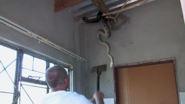 man with a shovel trying to catch and safely remove and relocate african rock python hiding in the corner of the room at a farm in Botswana