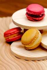 Primo piano di macarons alla crema con macarons ai frutti di bosco e alla fragola su sfondo di legno