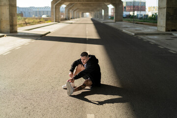 Chico joven tatuado y musculoso posando y haciendo deporte en la calle en un tunel con un puente de...