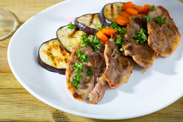 Fototapeta premium Tasty mutton loin chops grilled with eggplant slices and carrots garnished with fresh parsley