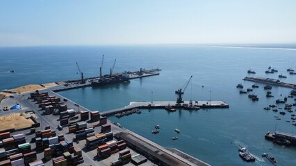 Drone shot of objects and cargo shops on a harbor under the blue sky