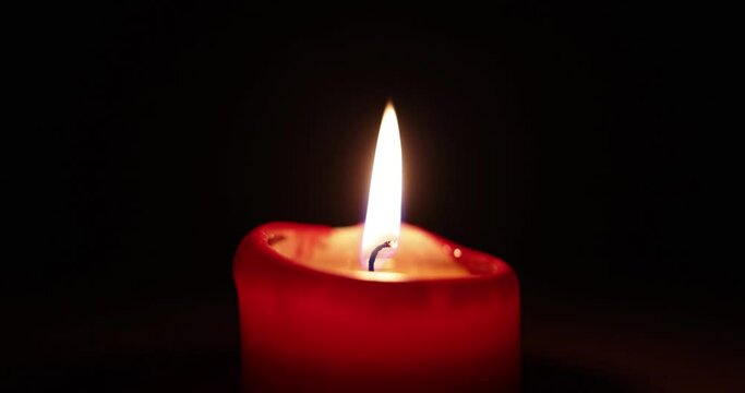 Ruhig brennende Kerze vor dunklem Hintergrund